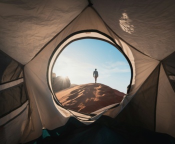 a man standing in a tent looking out into the distance